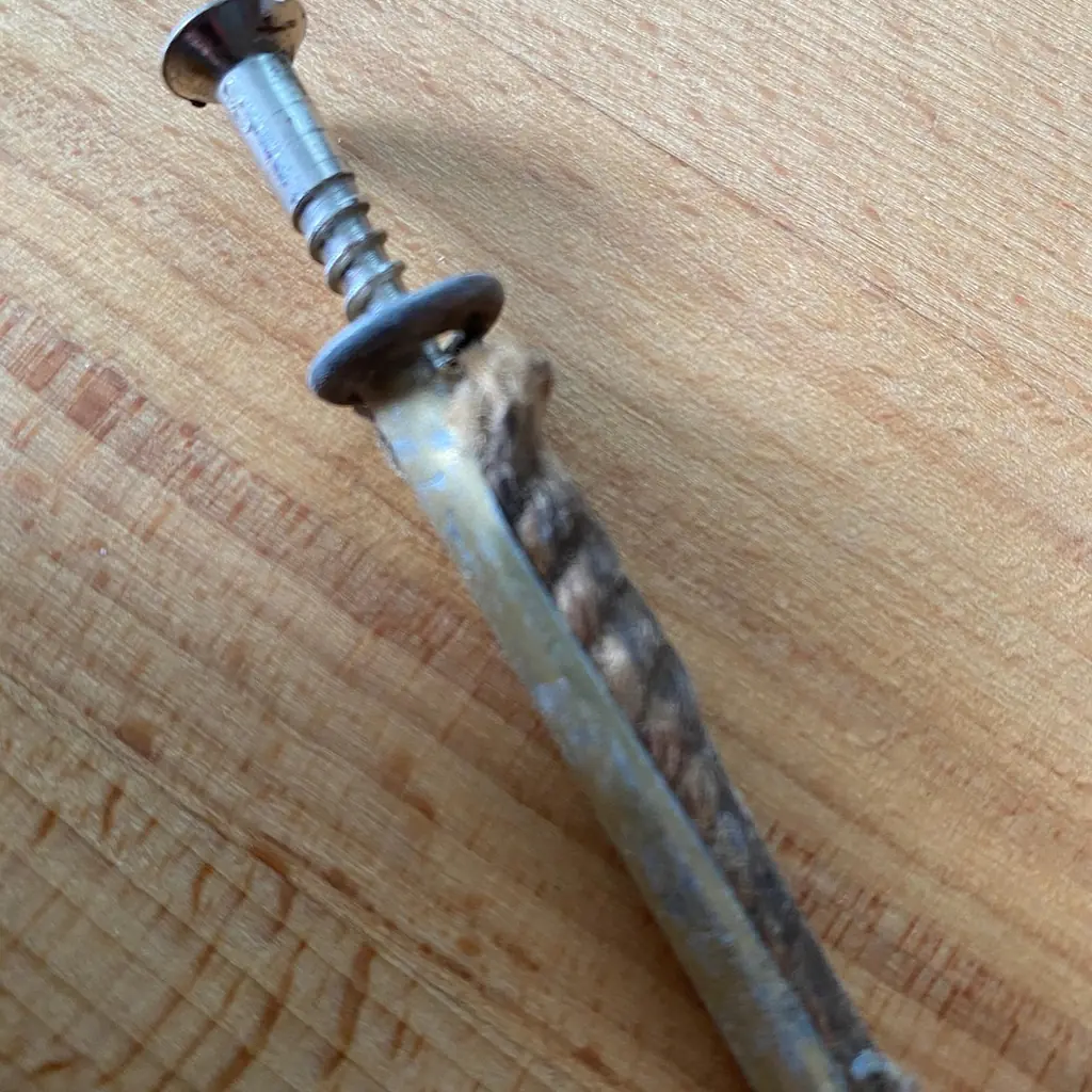 Wall plug and screw used to mount a shelf A wall plug and matching screw resting on a timber surface before being fitted.