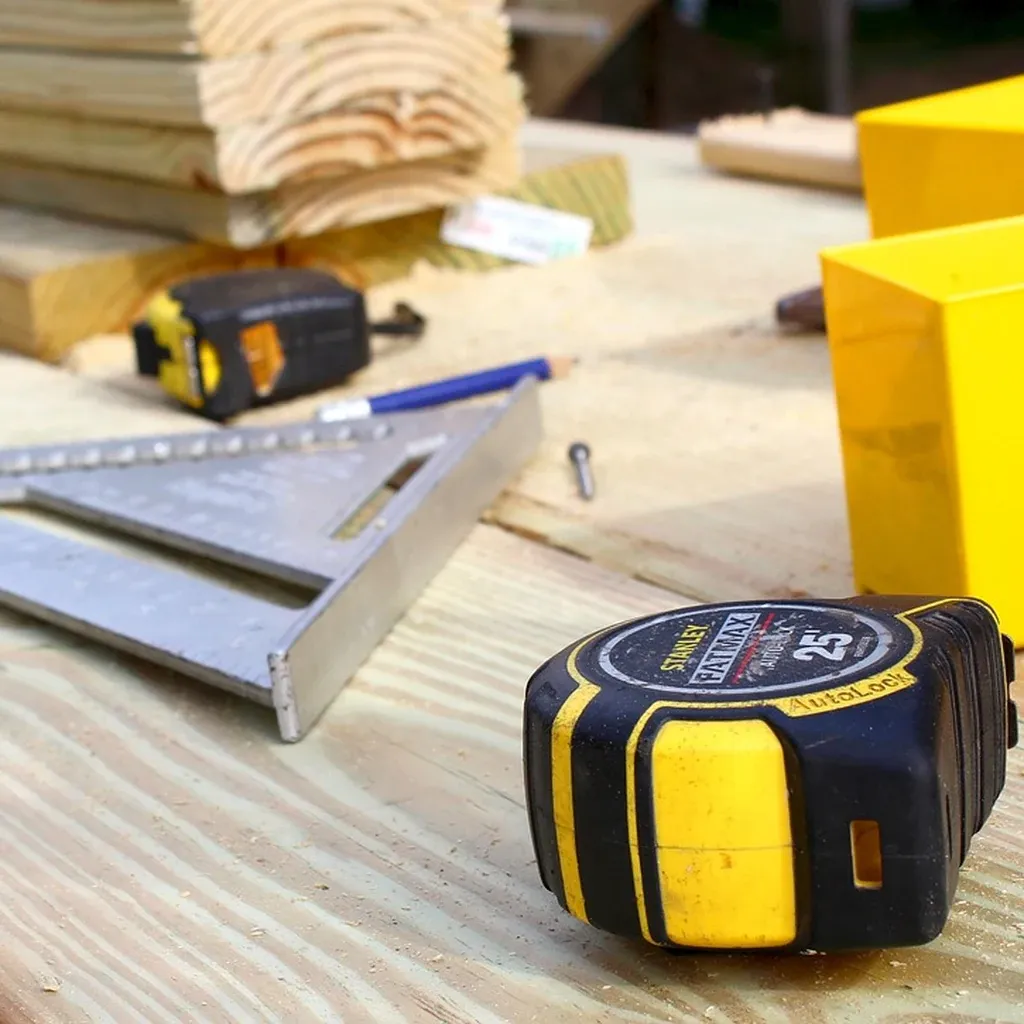 Measuring and marking tools for a plant stand A tape measure, combination square and pencil on a workbench beside cut lengths of timber.