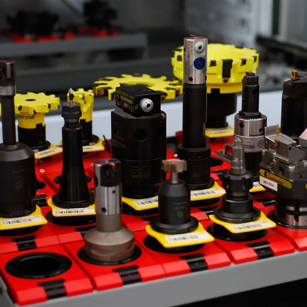 Bench vices providing dedicated work-holding A row of bench vices bolted along a workbench, jaws open and ready to clamp.