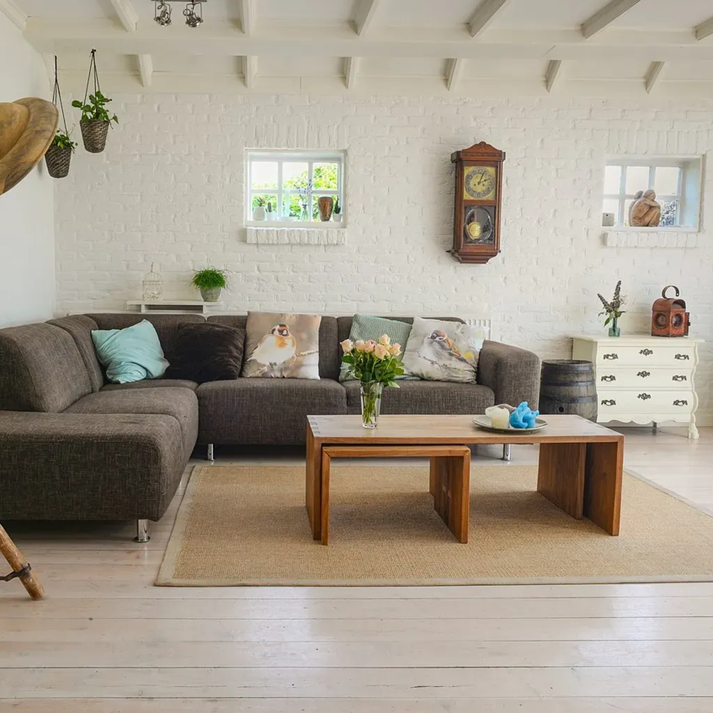 A bright living room with a sofa, a low wooden coffee table and a rug over a wooden floor.