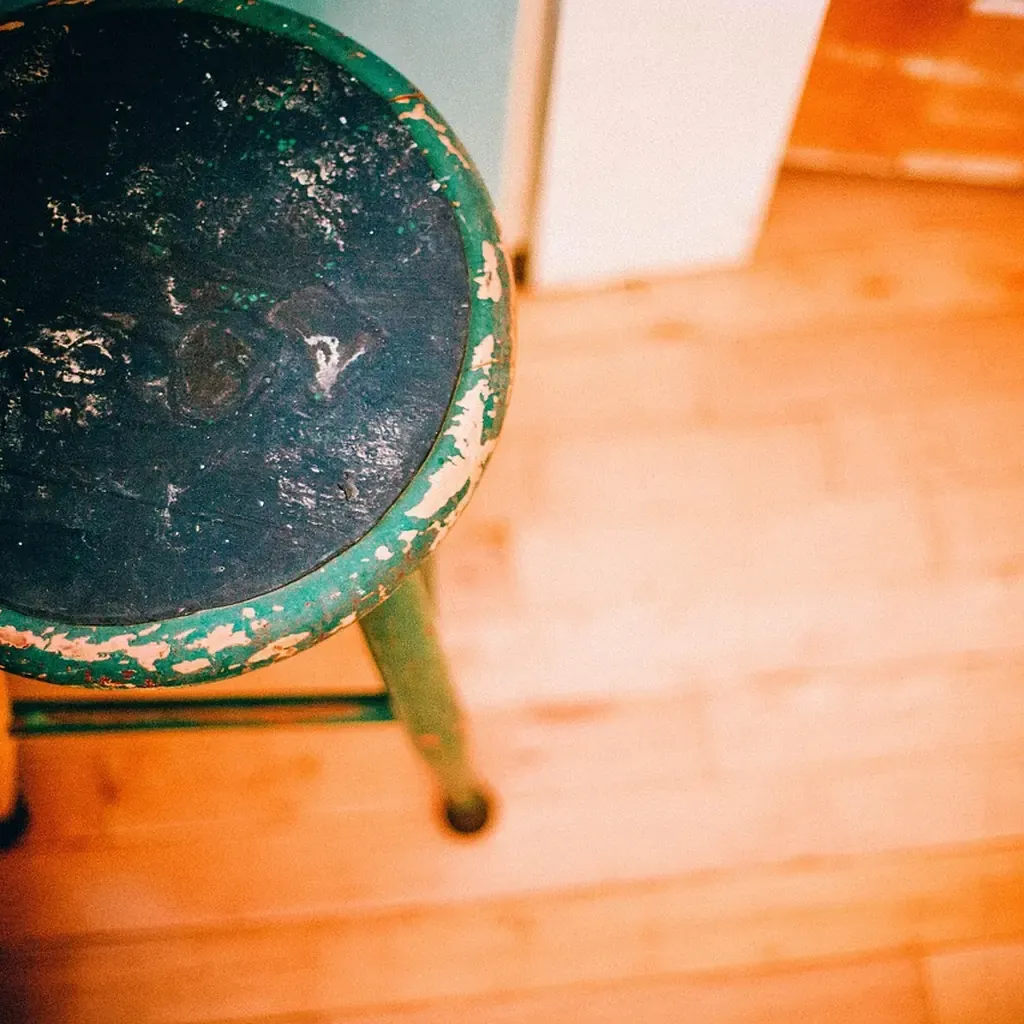 Checking a finished step stool before use A small painted wooden stool standing on a wooden floor, its joints and legs visible.
