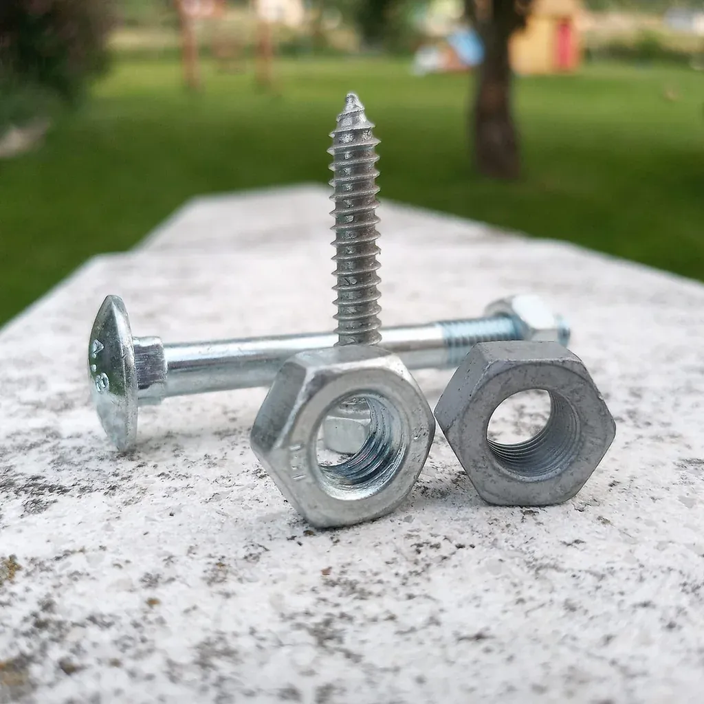 Screws used to reinforce a step stool joint Several coarse-threaded wood screws and nuts resting on a pale stone surface.