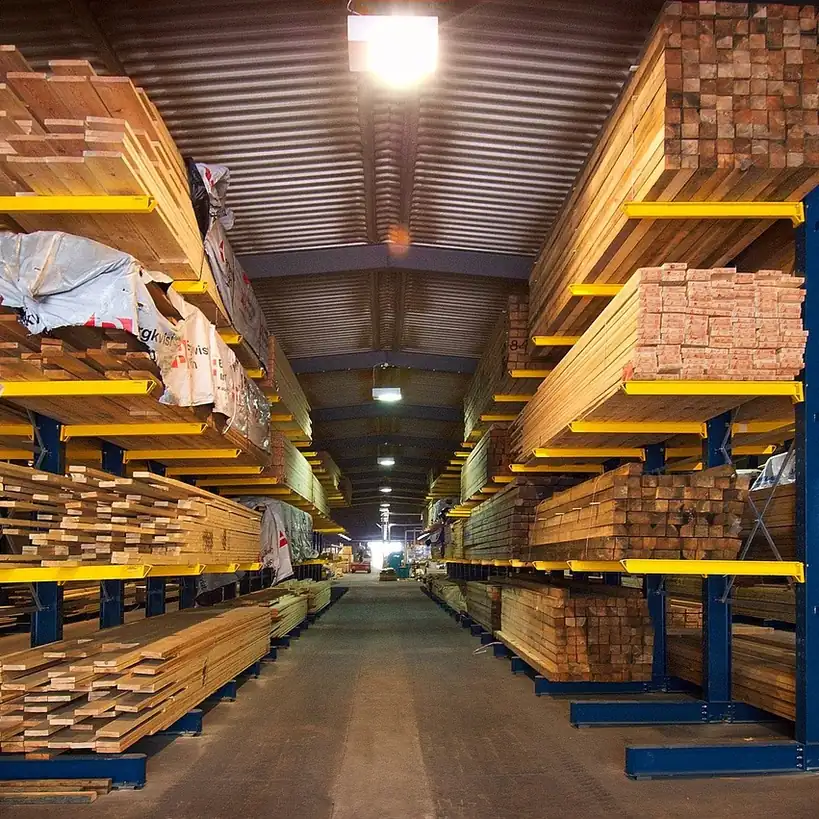 Lumber stored flat and fully supported Sawn timber stacked flat across steel racking in a long lumber store.