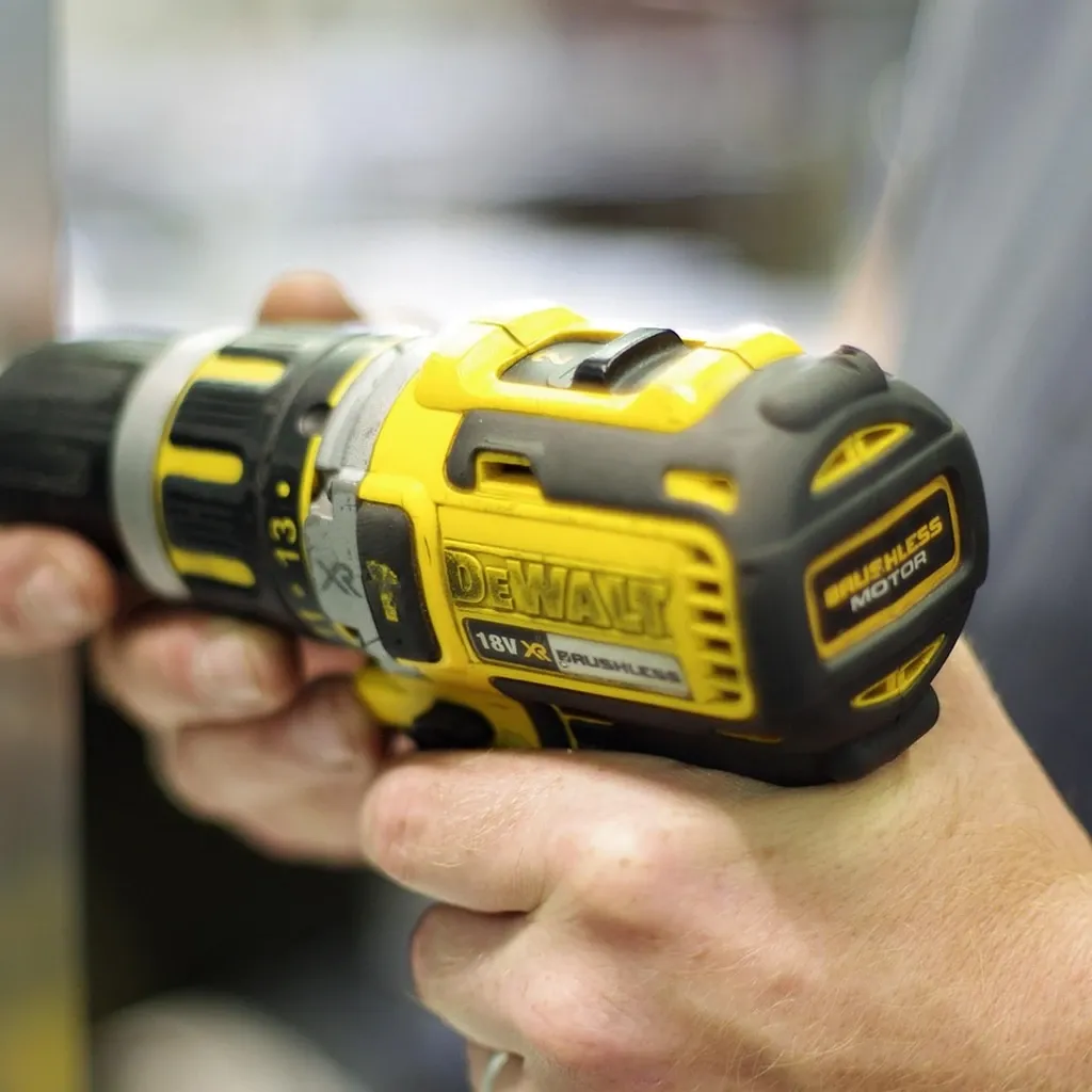 Cordless driver in use Hand holding a cordless driver while working on a piece of wood