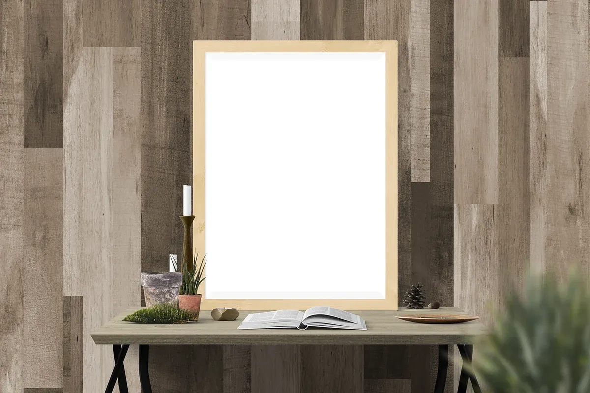 An empty wooden picture frame standing on a table against a plain wall.