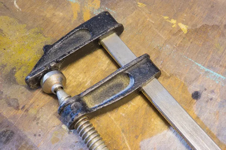 Two steel bar clamps resting on a scarred wooden work surface.