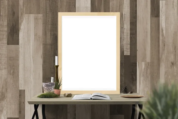 An empty wooden picture frame standing on a table against a plain wall.